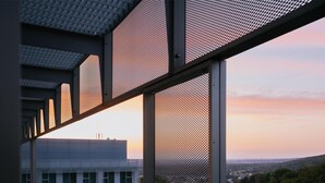 Un edificio moderno con vistas a un paisaje urbano y colinas al fondo.
