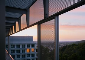 Un edificio moderno con vistas a un paisaje urbano y colinas al fondo.