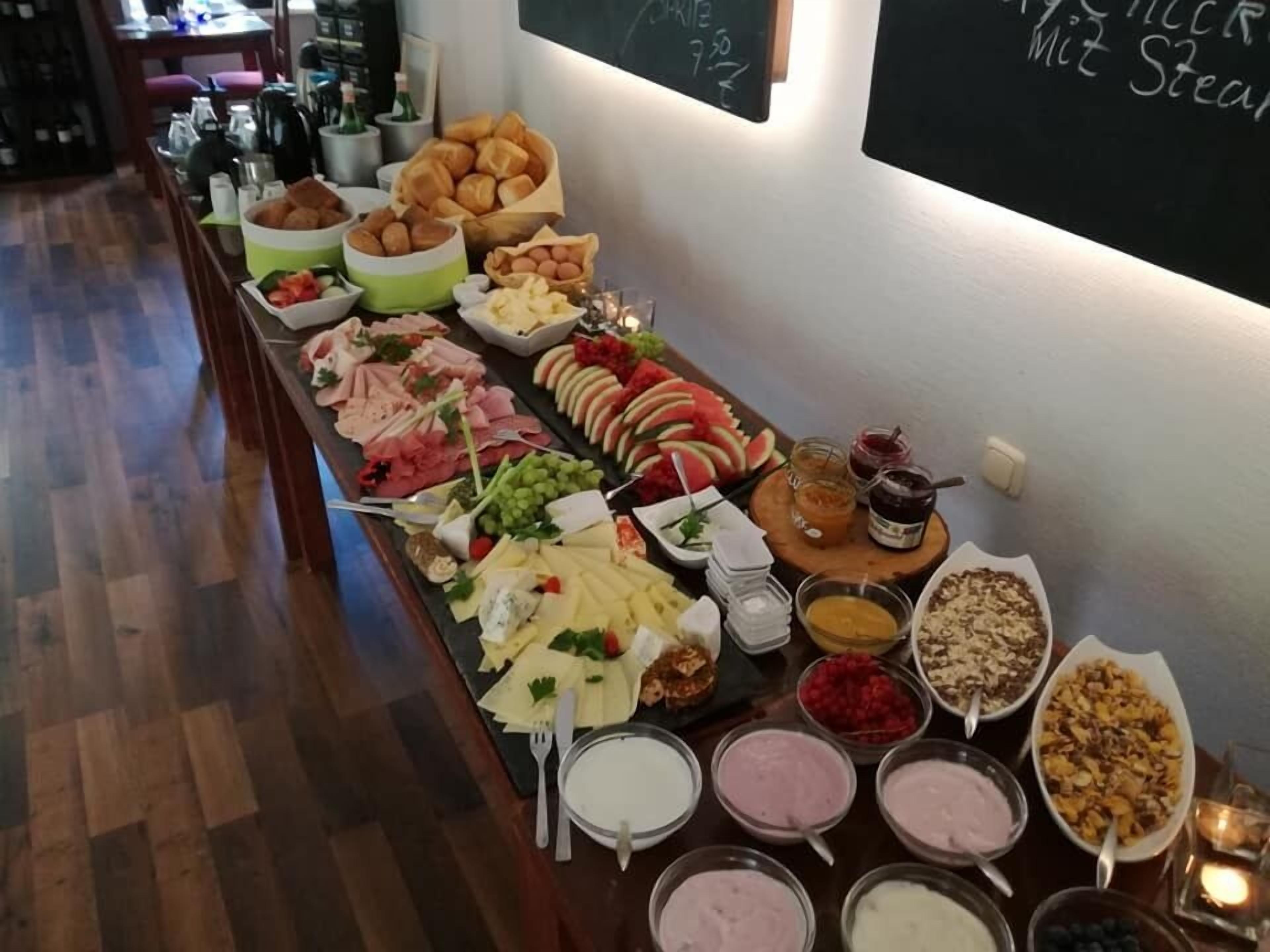 Ein Buffet mit verschiedenen Speisen, darunter Fleisch, Käse, Obst und Desserts.