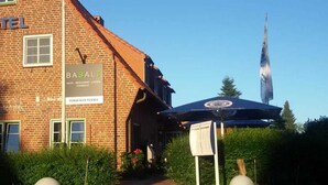 A brick building with a sign reading "HOTEL BASALT" and "FLAMENKIRCH PISSEY." - BASALT Hotel Restaurant Lounge (Hohwacht)