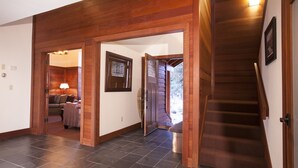 A spacious hallway with dark tiled flooring, wooden beams, and a staircase leading to an upper level. - Northstar Luxury Lodgepole 4 Bedroom Home by RedAwning (Truckee)