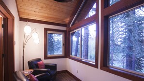 A cozy room with a leather chair, large windows, and a wooden ceiling. - Northstar Luxury Lodgepole 4 Bedroom Home by RedAwning (Truckee)