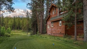 A wooden cabin with a porch, surrounded by a forest and a golf course. - Northstar Luxury Lodgepole 4 Bedroom Home by RedAwning (Truckee)