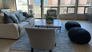 A spacious living room with a beige sofa, a coffee table, and two black ottomans.