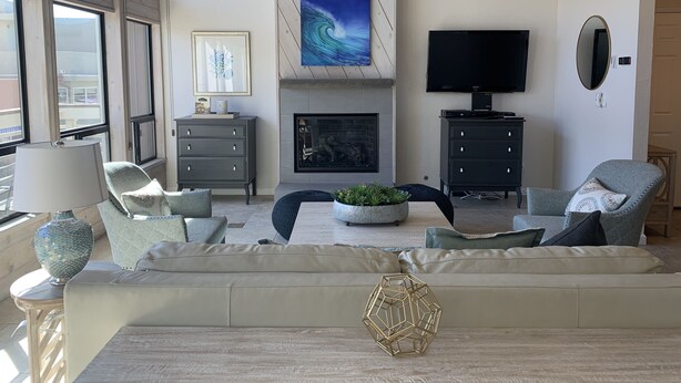 A modern living room with a fireplace, a television, and a large window.