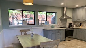 A kitchen with a dining table, chairs, a stove, and cabinets.