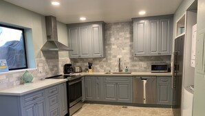 A modern kitchen with grey cabinets, a stainless steel dishwasher, a microwave, and a built-in oven.