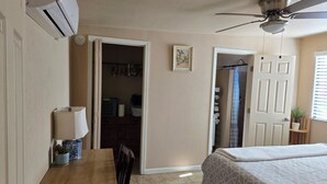 A bedroom with a bed, a desk, a chair, a ceiling fan, and a closet.