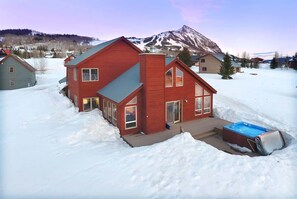 Uma casa vermelha com um alpendre grande e uma banheira de hidromassagem na neve.