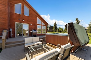 A wooden deck with outdoor furniture, a hot tub, and a grill.