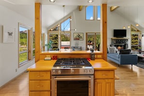A modern kitchen with a stove, oven, and large windows.