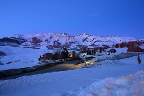 Paisagem montanhosa coberta de neve com casas e uma estrada.