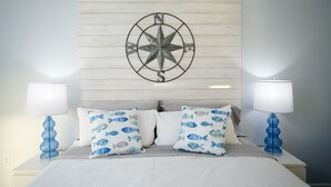 A bedroom with a bed, two nightstands, two lamps, and a wall-mounted compass.