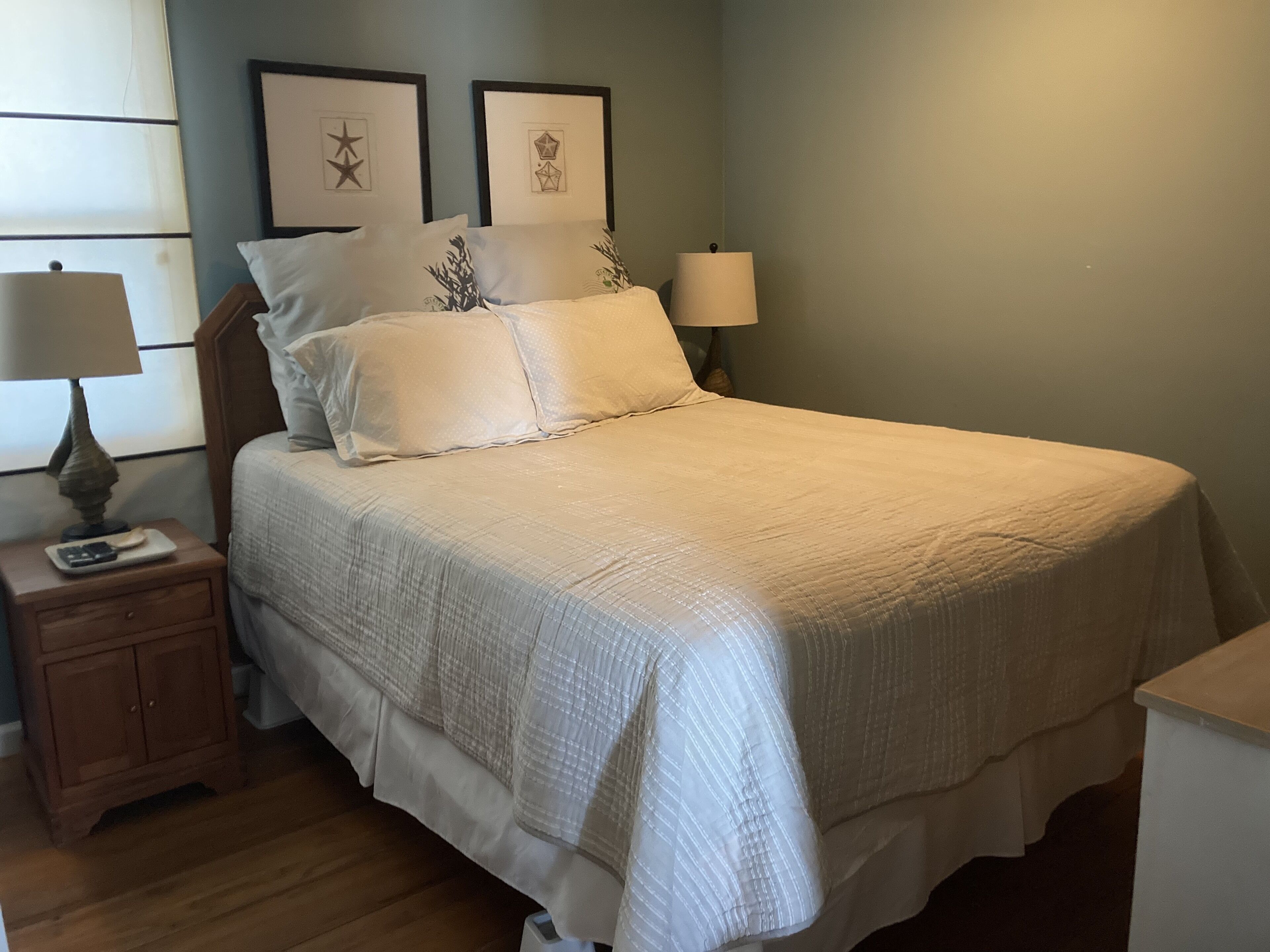 A bedroom with a bed, nightstands, and wall art.