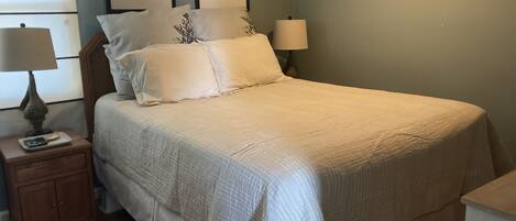 A bedroom with a bed, nightstands, and wall art.