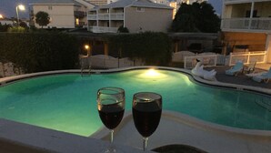 Piscina com dois copos de vinho tinto na borda.