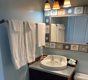 A bathroom with a sink, two towels hanging on a rack, a mirror with a decorative frame, and a wooden vanity. - Family Friendly & Quiet Riverside Condo with Pool & Fishing Piers (Pensacola)