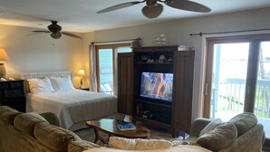 Quarto com cama, sofá, televisão e ventoinha no teto.