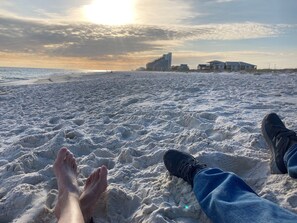 A beach scene with a person lying on the sand, facing the ocean. - Family Friendly & Quiet Riverside Condo with Pool & Fishing Piers (Pensacola)