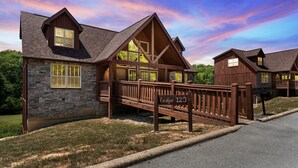 Un chalet avec une façade en pierre, une terrasse en bois et un ciel dégagé.