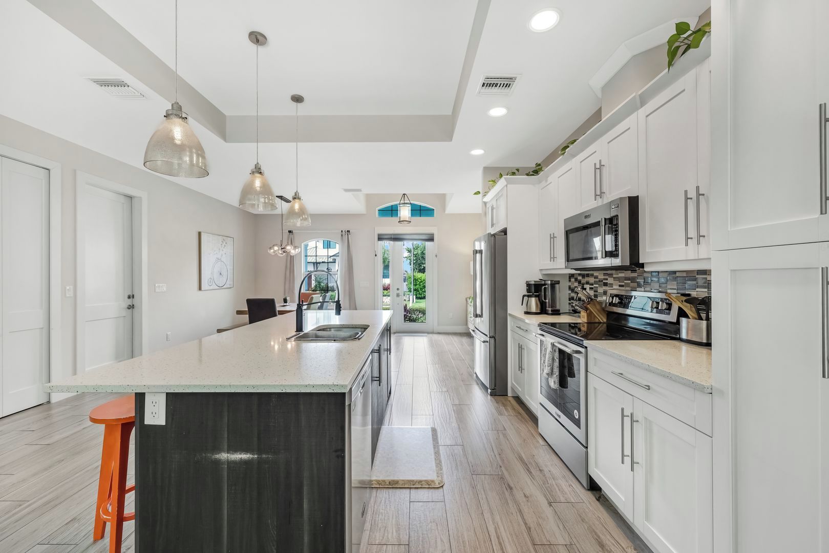 A modern kitchen with a central island, stainless steel appliances, and pendant lighting.