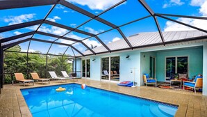 A swimming pool with lounge chairs and a covered patio area. - ISLAND LIFESTYLE FAMILY VACATION HOME (BRAND NEW) (Naples)