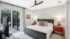A bedroom with a large bed, a ceiling fan, a TV, and a sliding glass door leading to an outdoor area. - ISLAND LIFESTYLE FAMILY VACATION HOME (BRAND NEW) (Naples)