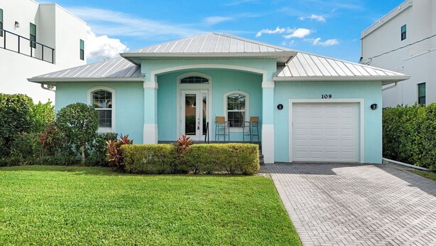 A modern two-story house with a light blue exterior, a white garage door, and a well-maintained lawn. - ISLAND LIFESTYLE FAMILY VACATION HOME SALT POOL (Naples)