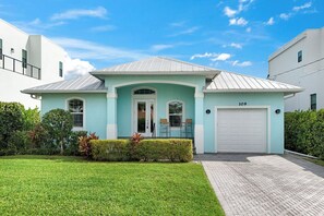 A modern two-story house with a light blue exterior, a white garage door, and a well-maintained lawn.