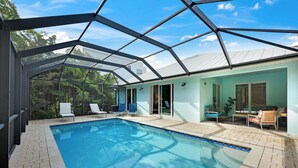 A swimming pool with a glass enclosure, surrounded by lounge chairs and a patio area. - ISLAND LIFESTYLE FAMILY VACATION HOME SALT POOL (Naples)