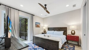 A bedroom with a bed, a nightstand, a desk with a computer, a ceiling fan, and a window with curtains. - ISLAND LIFESTYLE FAMILY VACATION HOME SALT POOL (Naples)