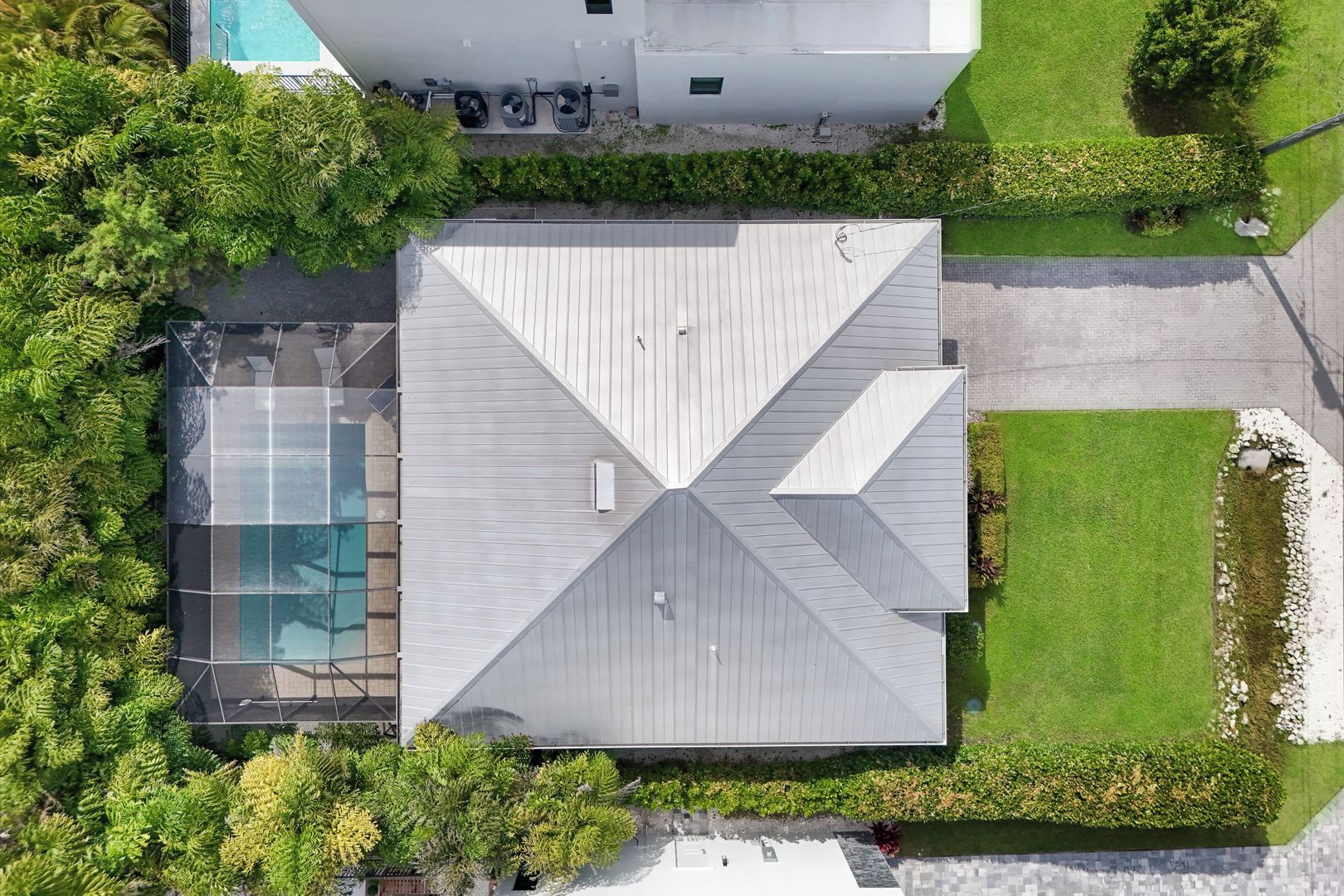 Un edificio moderno con diseño de techo simétrico, piscina y zonas verdes bien cuidadas.