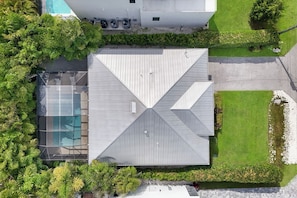 A modern building with a symmetrical roof design, a swimming pool, and well-maintained surrounding greenery. - ISLAND LIFESTYLE FAMILY VACATION HOME SALT POOL (Naples)