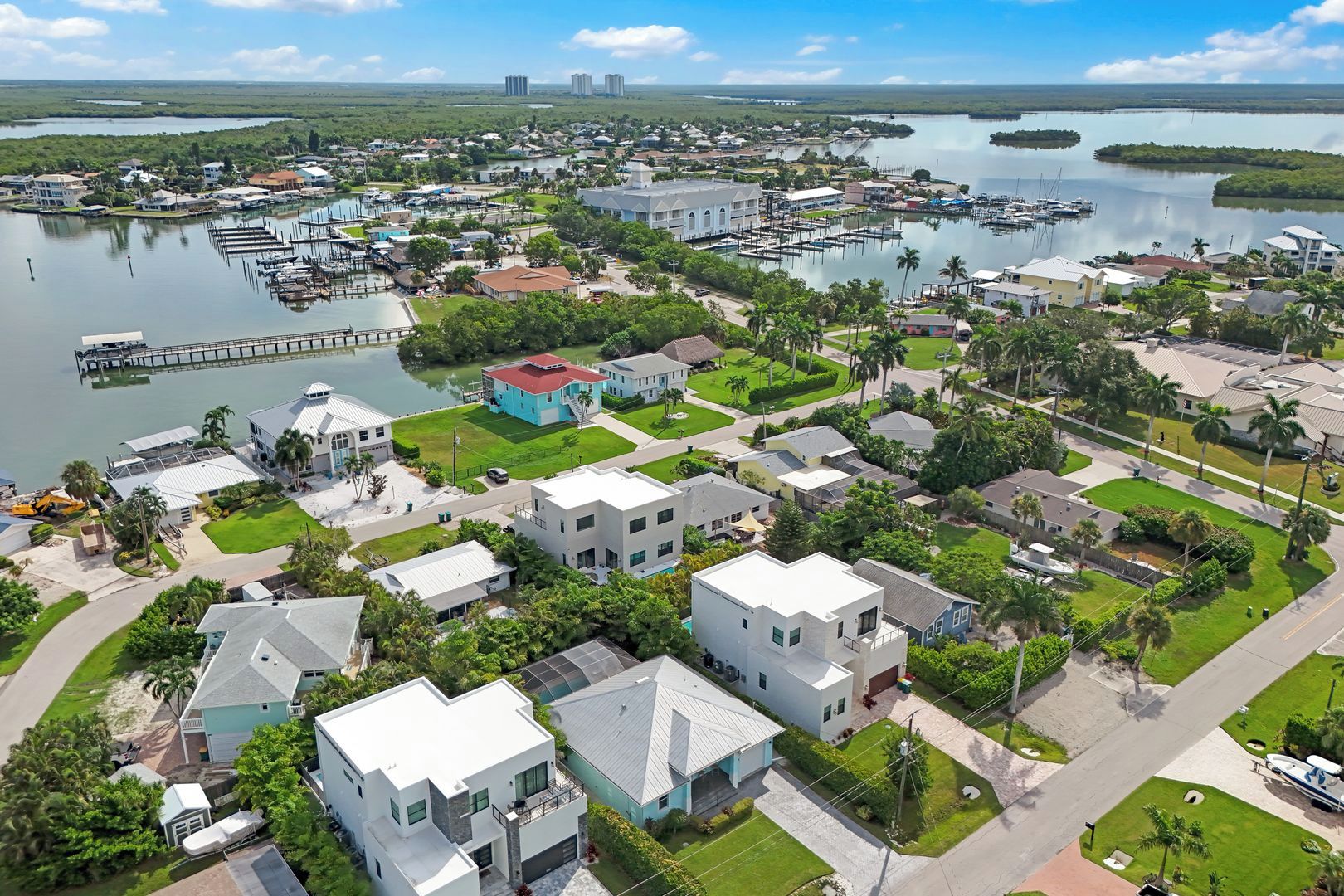 Un quartier résidentiel avec des maisons modernes, un port de plaisance et une jetée qui s’avance dans une étendue d’eau calme.