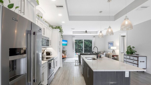 A modern kitchen with stainless steel appliances, a large island, pendant lighting, and a view of the outdoors. - ISLAND LIFESTYLE FAMILY VACATION HOME (BRAND NEW) (Naples)