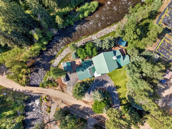 An aerial view of a property with a green-roofed building surrounded by dense trees and a river. - Beautiful Colorado log home backing to the Florida River. (Durango)