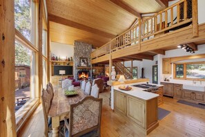 A spacious living area with a fireplace, wooden dining table, and a kitchen with a large island.
