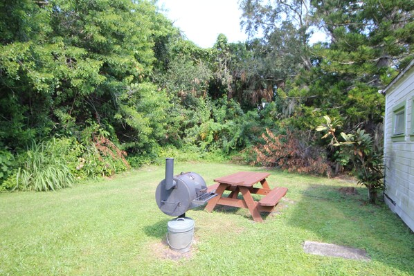 A backyard with a barbecue grill, picnic table, and a small shed.