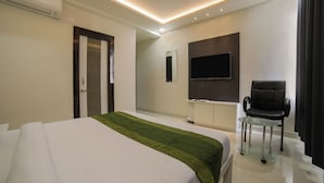 A modern hotel room with a large bed, a desk, a chair, and a flat-screen TV mounted on the wall. - Itsy Hotels Le Clover (Nagpur)