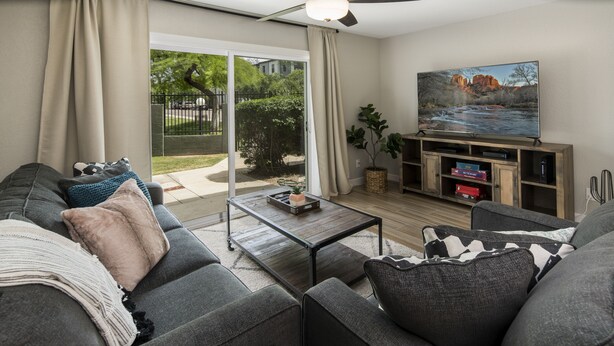 A modern living room with a grey sofa, a coffee table, and a flat-screen TV mounted on a wooden cabinet. - Walking distance to MIll Ave, Tempe Beach Park, Sun Devil Stadium, ASU. UPDATED! (Tempe)