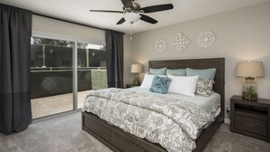 A bedroom with a large bed, a ceiling fan, two bedside tables with lamps, and a sliding glass door leading to a balcony. - Walking distance to MIll Ave, Tempe Beach Park, Sun Devil Stadium, ASU. UPDATED! (Tempe)