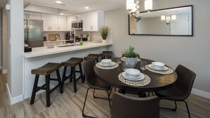 A modern kitchen with white cabinets, stainless steel appliances, and a dining area with a round table and six chairs. - Walking distance to MIll Ave, Tempe Beach Park, Sun Devil Stadium, ASU. UPDATED! (Tempe)