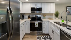 A modern kitchen with stainless steel appliances, white cabinetry, and a patterned rug. - Walking distance to MIll Ave, Tempe Beach Park, Sun Devil Stadium, ASU. UPDATED! (Tempe)