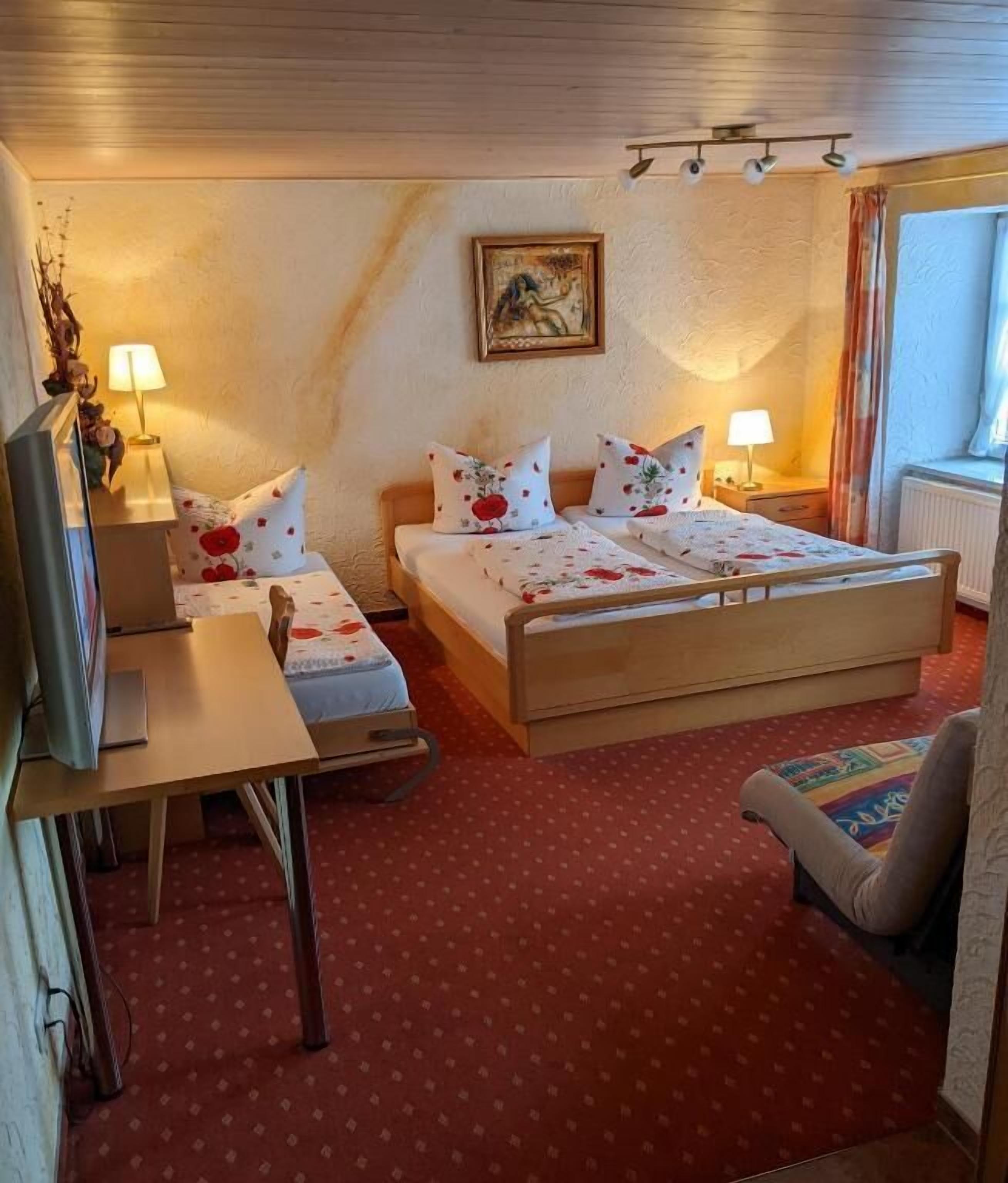 Hotellihuone, jossa on sänky, yöpöydät, työpöytä, tuoli ja ikkuna.