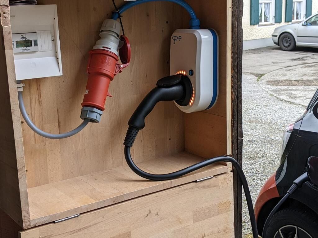 Eine tragbare Stromstation mit einer roten und weißen Pumpe, verbunden mit einem schwarzen Kabel und einem blauen Ladekabel.