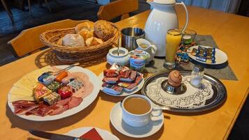 A breakfast setting with various food items, a coffee cup, and a jug of orange juice on a wooden table.