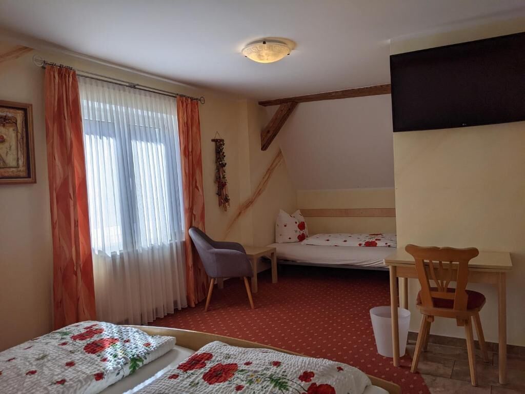 Una camera da letto con un letto, una scrivania, una sedia e una finestra con tende.