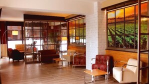 Un hall d’entrée spacieux au design moderne, avec différents types de sièges et de grandes fenêtres offrant une vue sur les vignobles.