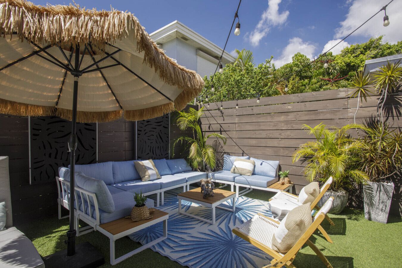 A patio with a sofa, a chair, a table, and a decorative umbrella.