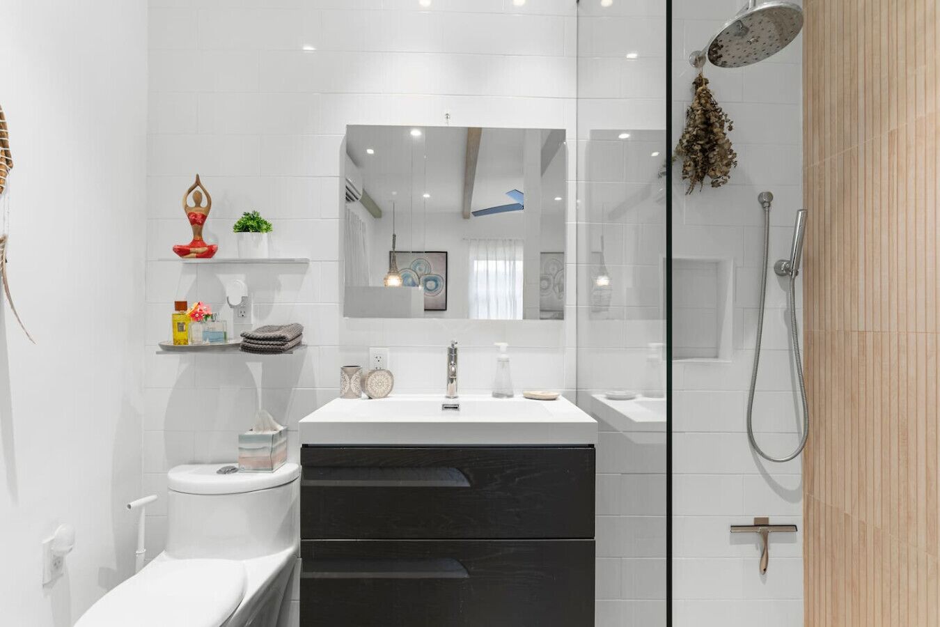 A modern bathroom with a white sink, black cabinet, and a glass shower enclosure.